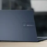 Asus Vivobook 14 trên bàn làm việc cùng cốc cà phê, thể hiện thiết kế mỏng nhẹ và màn hình sắc nét
