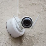 Camera an ninh không dây màu trắng gắn tường, minh họa việc truy cập hệ thống giám sát từ xa qua Port Forwarding