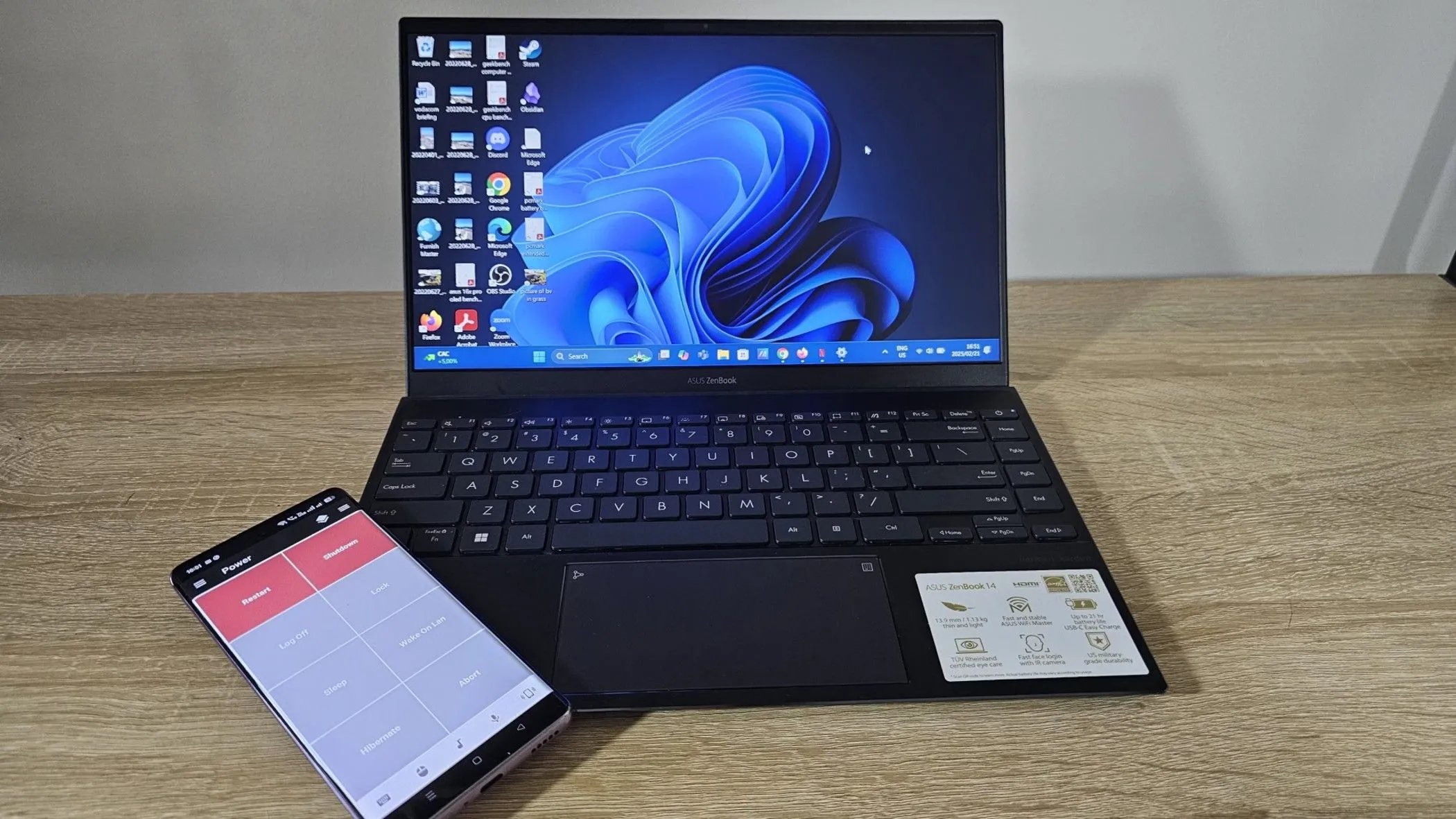 Laptop Asus ZenBook hiển thị Windows 11 và điện thoại Android, minh họa việc khôi phục dữ liệu hoặc điều khiển từ xa.