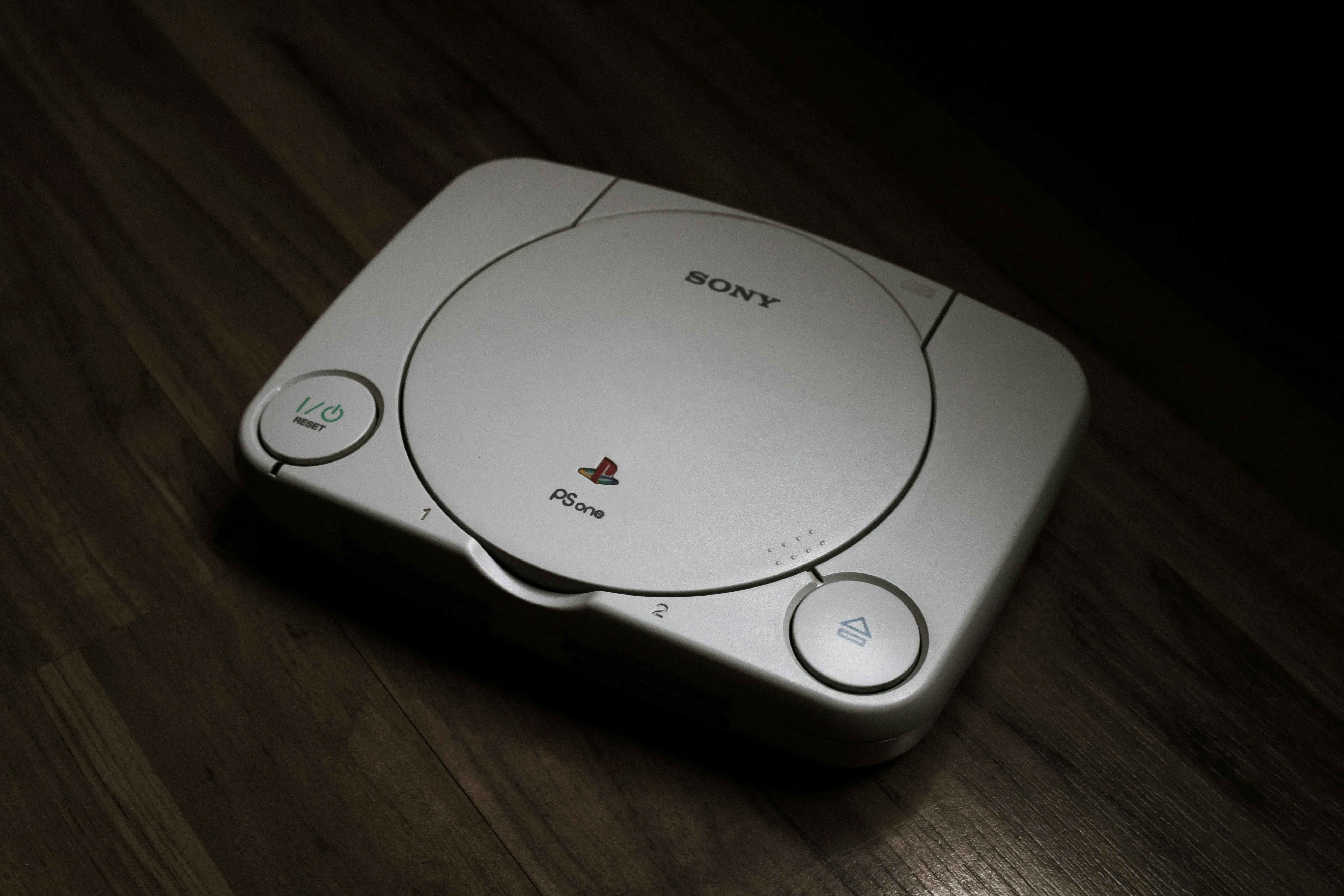 Máy chơi game PlayStation 1 đặt trên sàn gỗ, minh họa sự giao thoa phần cứng giữa console và PC