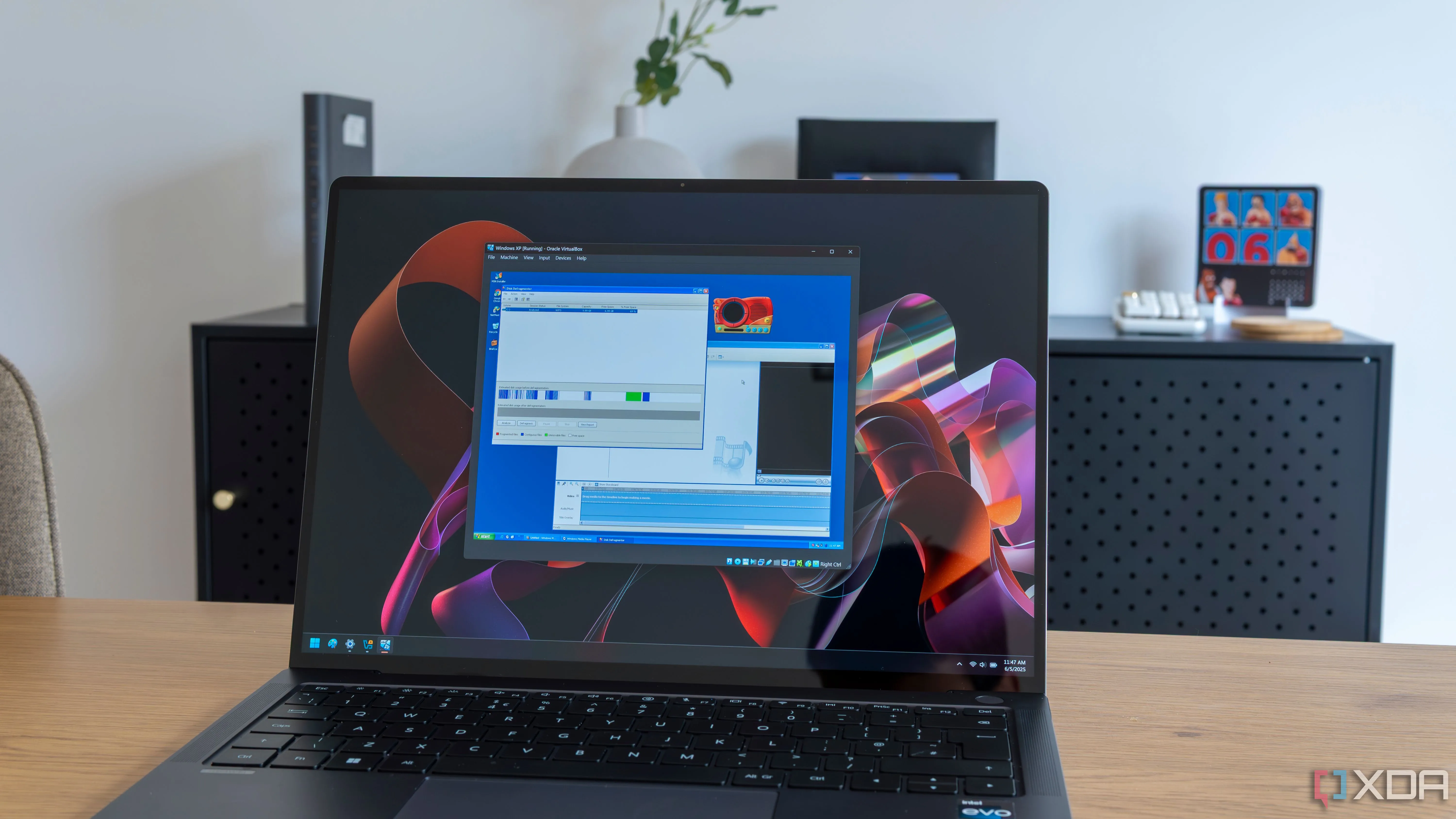 Máy tính xách tay Windows 11 hiển thị hình ảnh minh họa về máy ảo Windows XP, liên quan đến việc quản lý điểm khôi phục hệ thống.