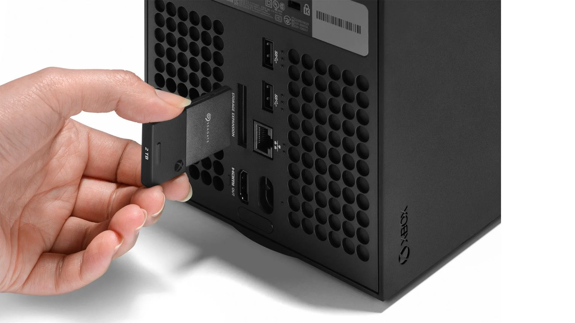 Một chiếc thẻ nhớ SSD mở rộng chính thức cho Xbox Series X đang được cắm vào khe cắm phía sau console, minh họa cách tăng dung lượng lưu trữ.