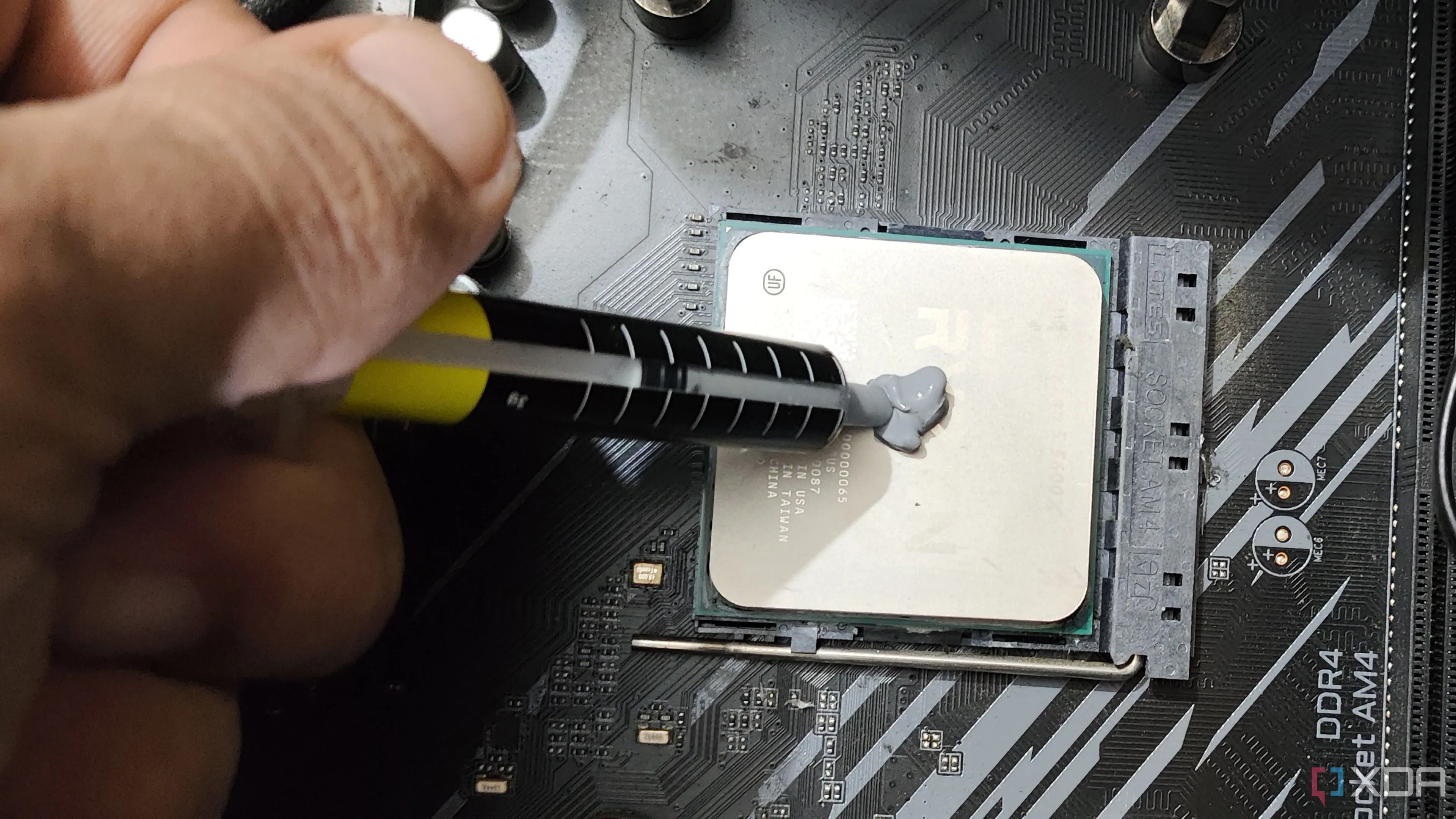Một người đang cẩn thận bôi keo tản nhiệt lên bề mặt bộ xử lý Ryzen 5 5600X